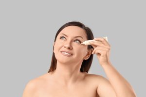 beautiful,adult,woman,with,tube,of,under eye,cream,on,white